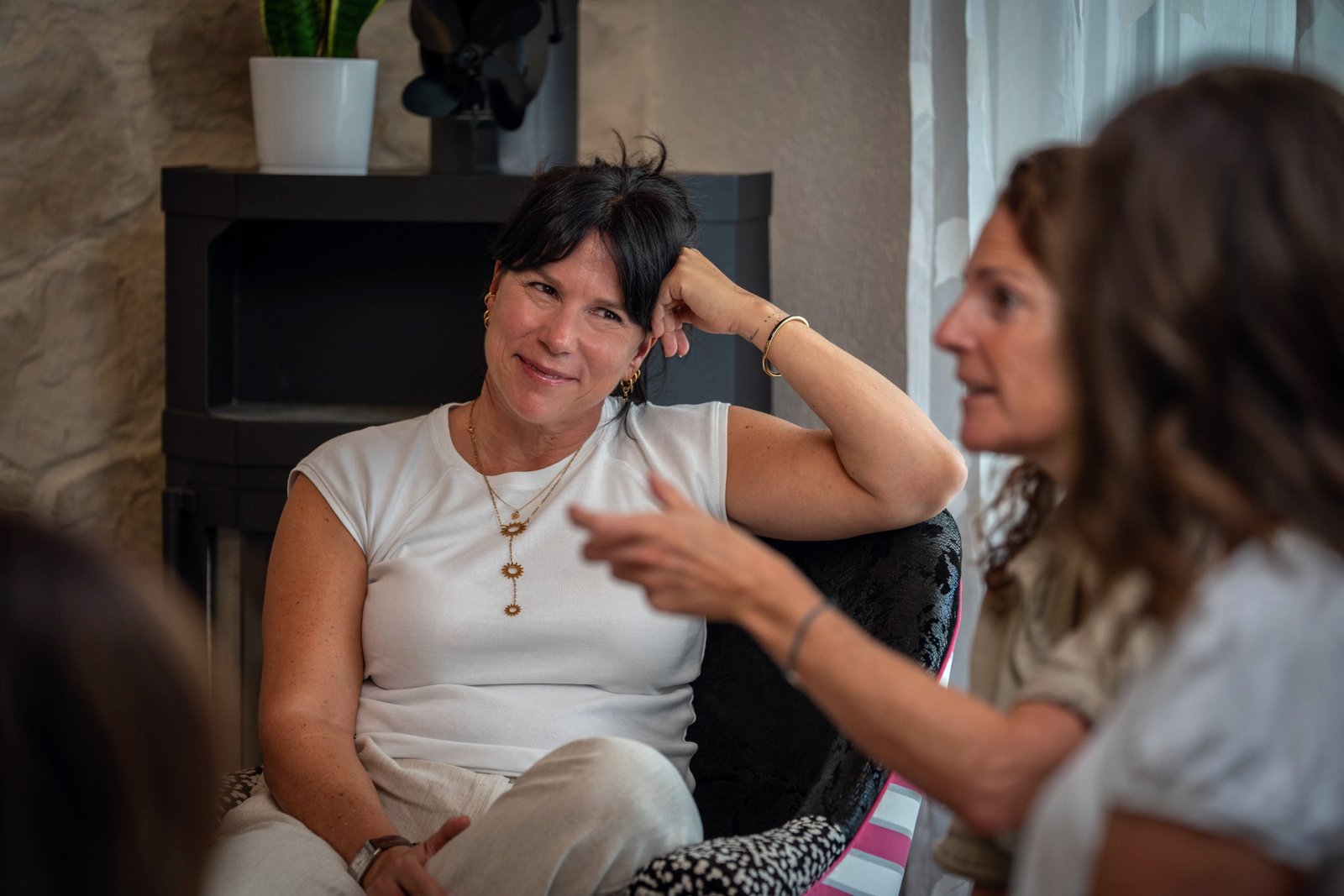 Valérie écoute en souriant, la main dans les cheveux, pendant qu’une participante parle